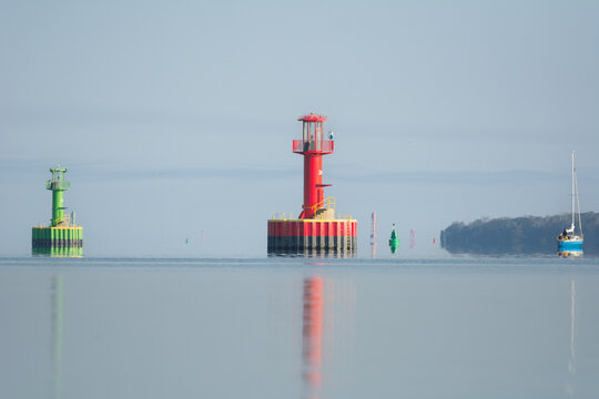 Lighthouse, navigation signs, buoyages, Buoys on calm blue water under blue sky. Photo from Szczecin Lagoon in Poland.