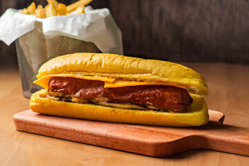 Hotdog Sausage Sandwich with Cheese and Fries isolated on wooden board side view of fast food on table