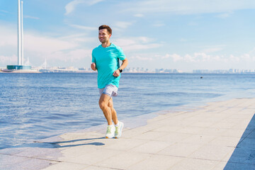 A Man Jogging Along the Waterfront Promenade on a Sunny Day, Enjoying the View of the City Skyline and Calm Water