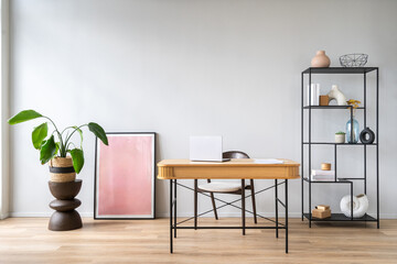 Workspace with a wooden desk, interior decor and indoor plants in home office