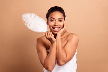 Photo of stunning dreamy lady hold cheerful feather bare shoulders isolated on beige pastel color...