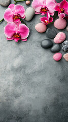 Pink orchid flowers and massage stones in spa setting on grey background for ultimate relaxation