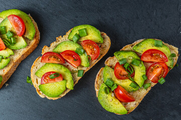 Avocado toast topped with tomato and green onion on a slice of carrot bread