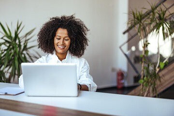 Smiling Professional Woman Working on Laptop in Modern Office