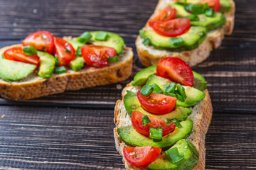 Avocado toast topped with tomato and green onion on a slice of carrot bread