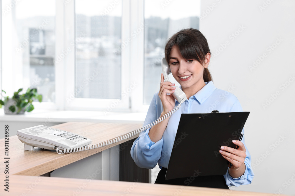 Wall mural Professional receptionist talking on phone in office