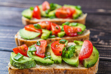 Avocado toast topped with tomato and green onion on a slice of carrot bread