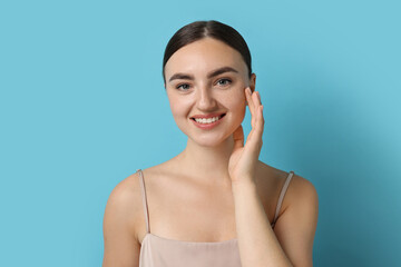 Naklejka premium Beautiful young woman with healthy skin on light blue background