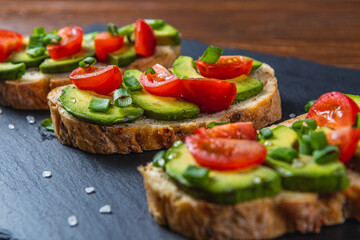 Avocado toast topped with tomato and green onion on a slice of carrot bread