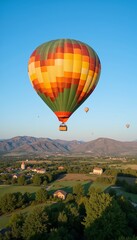 Fototapeta premium A brightly colored hot air balloon floating serenely in a clear blue sky, with a picturesque countryside below, evoking a sense of freedom and tranquility