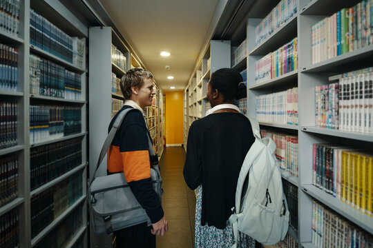 Students choosing books on the shelves together in the library