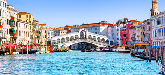 Panoramic view of Grand Canal with Rialto Bridge and gondoliers in Venice, Italy. Panorama of Rialto Bridge and gondola on the Grand Canal in Venice, Italy.