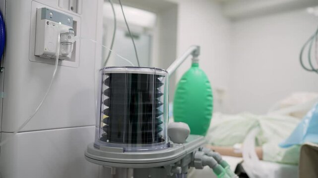 Medical ventilator standing near patient lying in hospital bed.