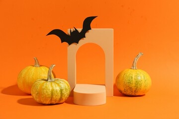 Halloween celebration. Black paper bat, pumpkins and geometric figures on orange background