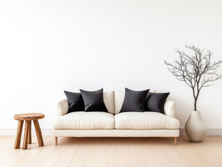 Cozy living room setup featuring a cream sofa with black cushions, a wooden stool, and a minimalist vase with a branch against a white wall
