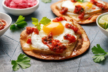 Huevos Rancheros tostadas with fried egg, tomato salsa, bean paste and cheese. Mexican food