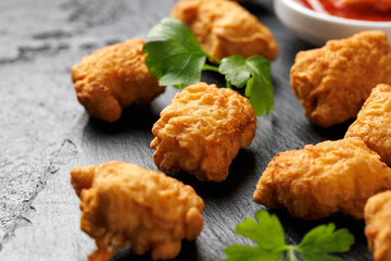 Homemade crispy fried chicken nuggets served on a stone board