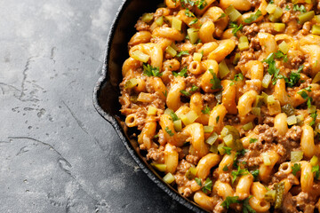 Cheeseburger Pasta with ground beef, melted cheese and gherkins in a iron cast pan