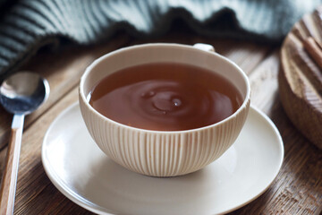 A cup of black tea stands on a wooden table