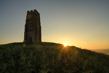 Silhouette of a historic tower Glastonbury Tor at sunrise on a hill © PetrDolejsek