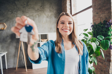 Photo of young attractive blonde hair realtor lady wearing blue casual shirt holding keys in loft...