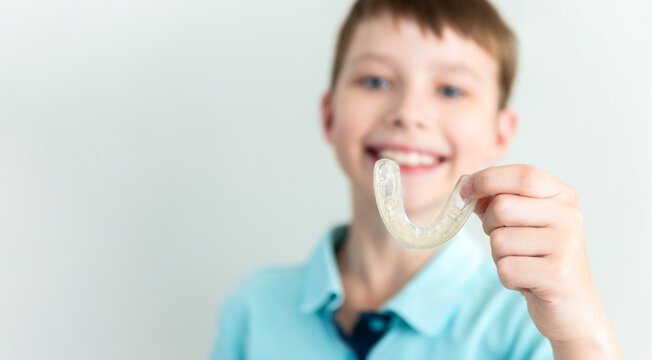 Little kid boy holding professional orthodontic removable invisible aligner. Dental healthcare and confidence concept
