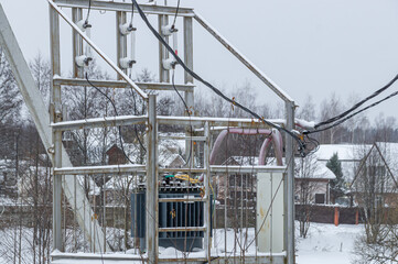 An electric transformer on the street in a rural area. Providing settlements with electricity. Electrical equipment for cities and villages. Transmission of electricity by wire.
