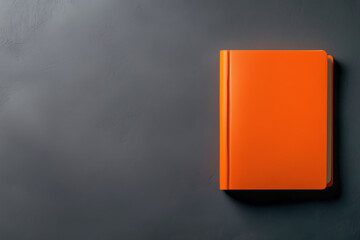 An orange notebook placed on a dark surface showcases simplicity and creativity in study sessions