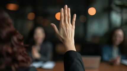 A woman's hand raised in a meeting, asking a question or volunteering an answer.
