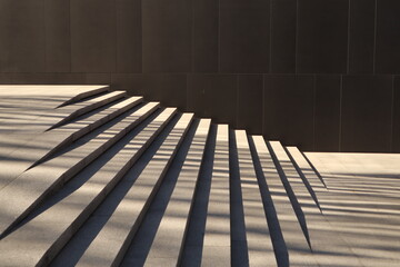 Stairs and Shadows.  Dark wall. The interplay of geometry, light, and shadow. Black wall of the building and light stairs