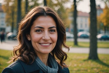 Close portrait of a smiling 40s Turkish woman looking at the camera, Turkish outdoors blurred background