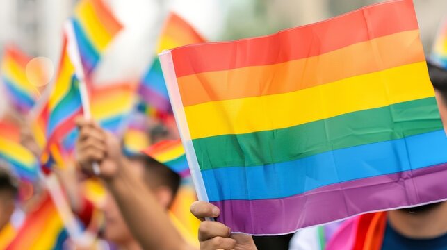 Close-up of rainbow pride flags waving at a pride parade.