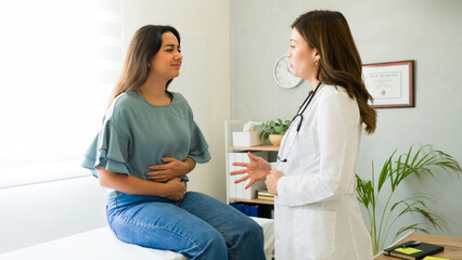 Female patient discusses her symptoms with a doctor during a medical appointment in a doctor's...
