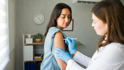 Hispanic woman is getting a vaccination from a healthcare worker, promoting overall wellness