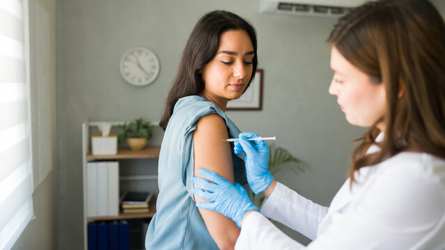 Hispanic woman is getting a vaccination from a healthcare worker, promoting overall wellness