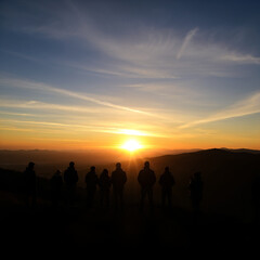 People watching sunrise over mountain ranges with a clear sky