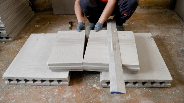 Construction worker assembling lightweight concrete blocks using a level