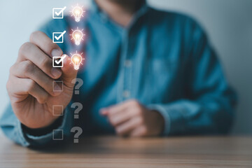 Businessman tick mark on glowing light bulb with question mark for select creative thinking idea...