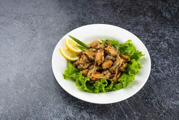 A plate of food with a green leafy salad and a lemon wedge on top