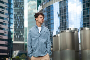 A young man stands at the Moscow City towers and looks into the distance