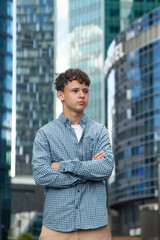 A young man stands at the Moscow City towers and looks into the distance
