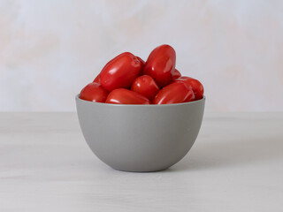 red cherry tomatoes in a bowl, front view, light background