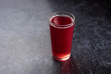 A glass of red liquid sits on a countertop
