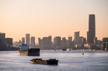 Fototapeta premium Ships on the Huangpu River and the city skyline in Shanghai at dusk.
