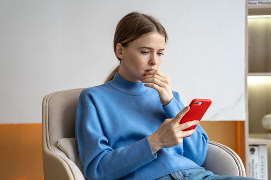 Fototapeta Distracted overwhelmed woman focused on smartphone, conducting business tasks remotely from home. Sad female managing online work, business issues, remote job, get bad news, scrolling web feed