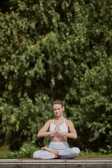 Blonde woman sitting in lotus position and meditating in calm atmosphere