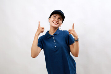 Young hispanic woman courier wearing delivery uniform and cap amazed and surprised looking up and pointing with fingers and raised arms.
