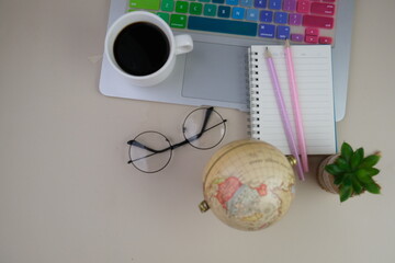 Flatlay of coffee with pink office tools, pink headphone, notebook, pen and a bouquet of pink tulips on pink background as copy space concept