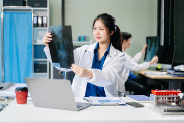 Confident young female doctor in white medical uniform sit at desk working on computer.