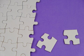 Fototapeta premium white jigsaw puzzle with missing puzzle for a text template. Above photo of isolated on the purple background